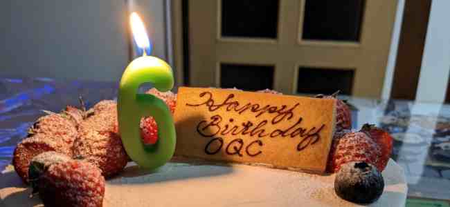 Picture of a cake with a green number six candle.