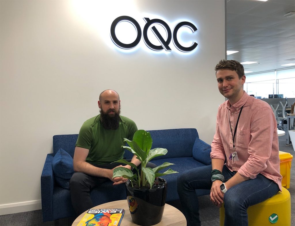 Quantum Tech engineers sitting in front of an OQC sign
