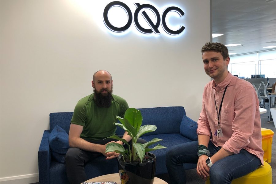 Quantum Tech engineers sitting in front of an OQC sign