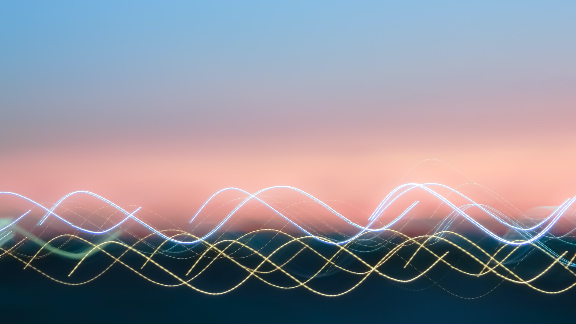 Image of blue and yellow sound waves going across a blurred sunset background