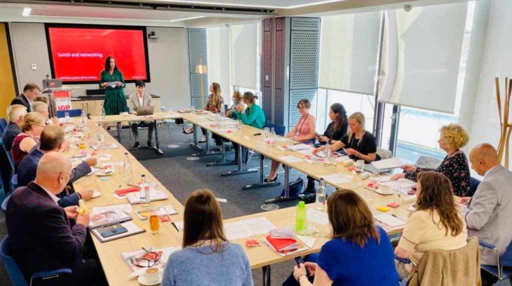 Image of people sitting around a table with a presentation screen in front of them